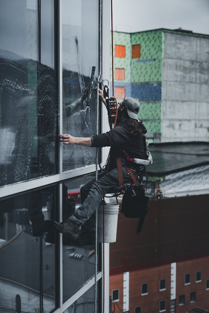 our-story-02 A man in a harness cleaning skyscraper windows with precision.