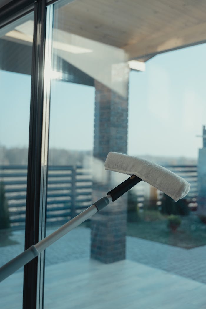 our-story-01 A modern cleaning tool used to clean a large glass window with a clear outdoor view.